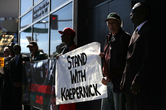 "Estamos com Kaepernick", diz cartaz  em manifestação contra o racismo nos EUA, em trocadilho com a palavra "stand" (Foto: Getty Images)