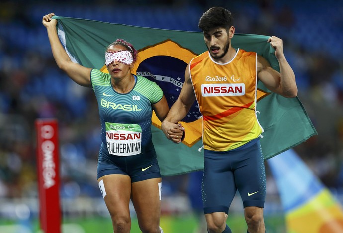 Descrição da imagem: Terezinha Guilhermina comemora a medalha de bronze com bandeira do Brasil (Foto: REUTERS)