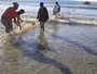 Moradores da Cidade do Cabo consertam rede contra tubarões