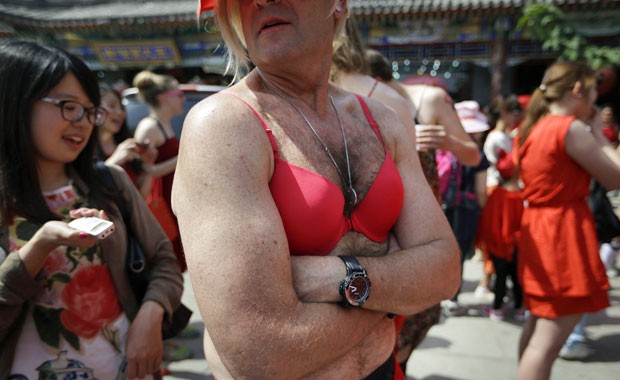 Homem usando sutiã vermelho aguarda o início da corrida, em Pequim, neste domingo (12) (Foto: Jason Lee/Reuters)