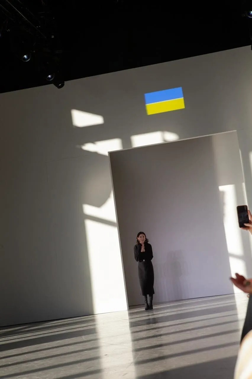 Svitlana Bevza em seu desfile de outono de 2022 na New York Fashion Week em 15 de fevereiro de 2022. Acima dela está uma projeção da bandeira ucraniana. (Foto: Arquivo pessoal)