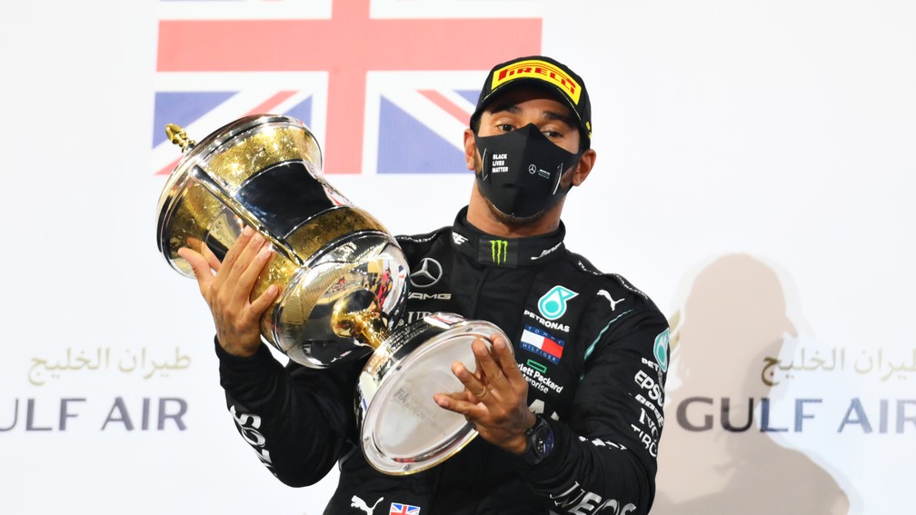 Lewis Hamilton comemora a vitória no GP do Bahrein de 2023 com o troféu no pódio — Foto: Clive Mason/F1 via Getty Images