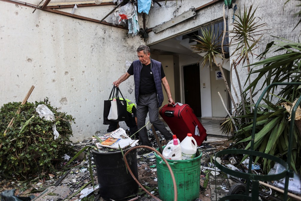 Um homem é visto com malas ao sair de um prédio que acabou de ser destruído após um ataque de foguete de Gaza em Ashdod, Israel, nesta segunda (17)  — Foto: Ronen Zvulun/Reuters