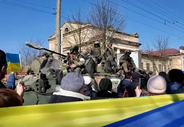 Ativistas pró-Ucrânia em frente a soldados russos durante uma manifestação em Kherson (Foto: BBC)