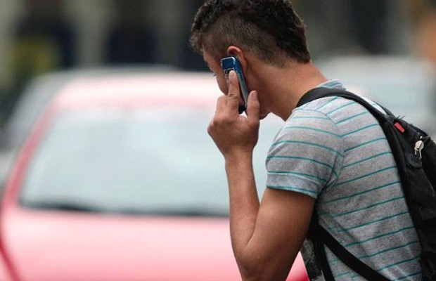 Jovem usa celular ao atravessar a rua no Rio de Janeiro (Foto: Agência O Globo)
