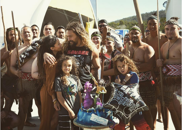O ator Jason Momoa, com esposa, filhos e amigos e com o bolo do Aquaman (Foto: Instagram)
