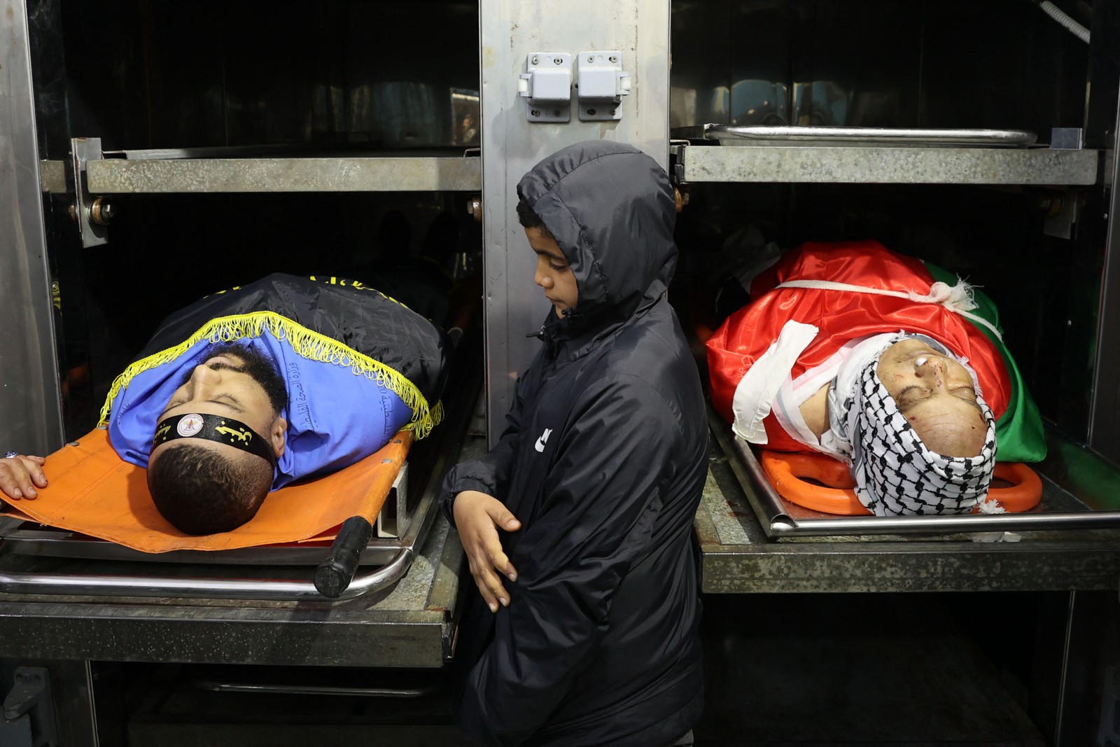 Menino palestino chora ao lado dos corpos de Jawad Farid Bawaqna, 57 anos, e Adham Mohammed Bassem Jabareen, 28, no necrotério de um hospital. Os dois foram mortos por tiros durante ataque do exército israelense na cidade de Jenin, no norte da Cisjordânia — Foto: Zain Jaafar / AFP