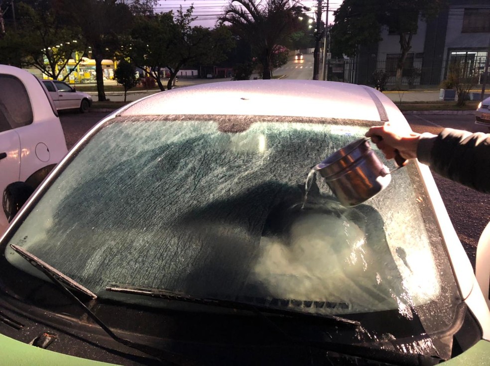 Pessoas usam água quente para descongelar vidro de carro em Piedade — Foto: Diogo Nolasco/TV TEM 