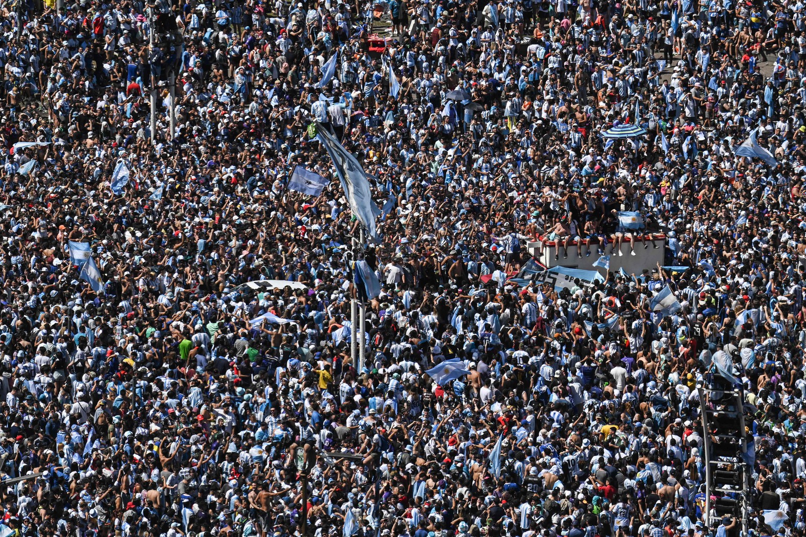 Torcedores da Argentina esperam o ônibus com os jogadores da Argentina para passar pelo Obelisco para comemorar após vencer a Copa do Mundo do Catar 2022 em Buenos Aires — Foto: Luis ROBAYO / AFP