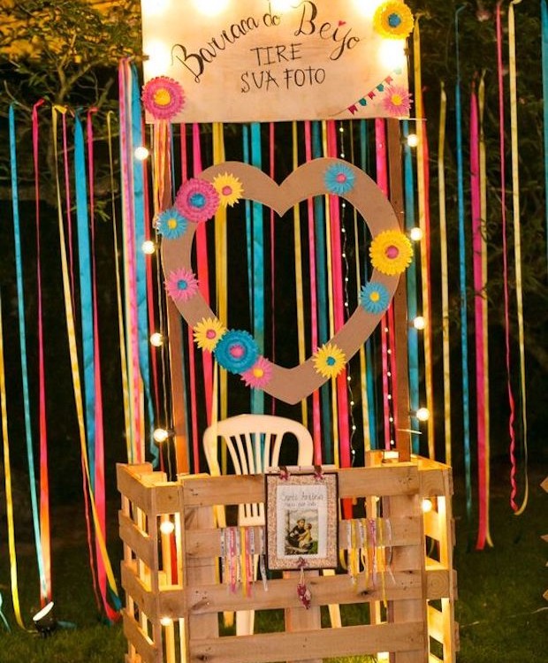 Com alguns palets, fitas e cartazes dá para montar uma barraca do beijo no quintal de casa (Foto: Autoria Eventos / Pinterest)