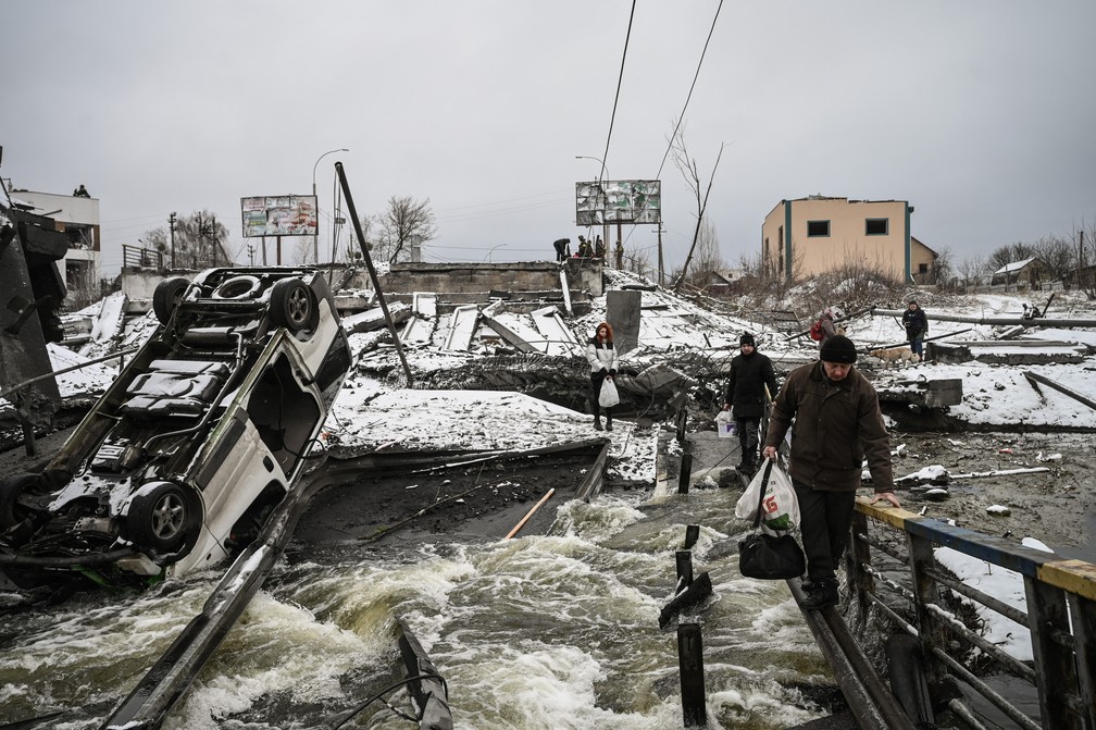 1º de março - Civis cruzam uma ponte destruída por bombardeio na parte norte de Kiev, capital da Ucrânia — Foto: Aris Messinis/AFP