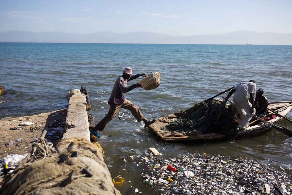 Um pescador pula em um barco de madeira, em Porto PrÃ­ncipe, no Haiti, paÃ­s que ocupa a posiÃ§Ã£o 168 de 189 do Ãndice de Desenvolvimento Humano  â€” Foto: Dieu Nalio Chery/AP