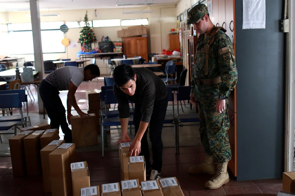 Funcionário eleitorais arrumam sala de votação para o segundo turno presidencial deste domingo (17) no Chile (Foto: Pablo Sanhueza/ Reuters)