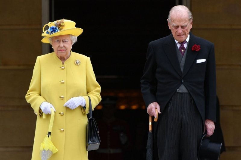 BBC Ao lado da rainha, o duque observou um minuto de silêncio no início de uma festa no jardim no Palácio de Buckingham, em 23 de maio de 2017, em homenagem aos mortos depois do atentado no show de Ariana Grande, em Manchester (Foto: PA MEDIA via BBC)