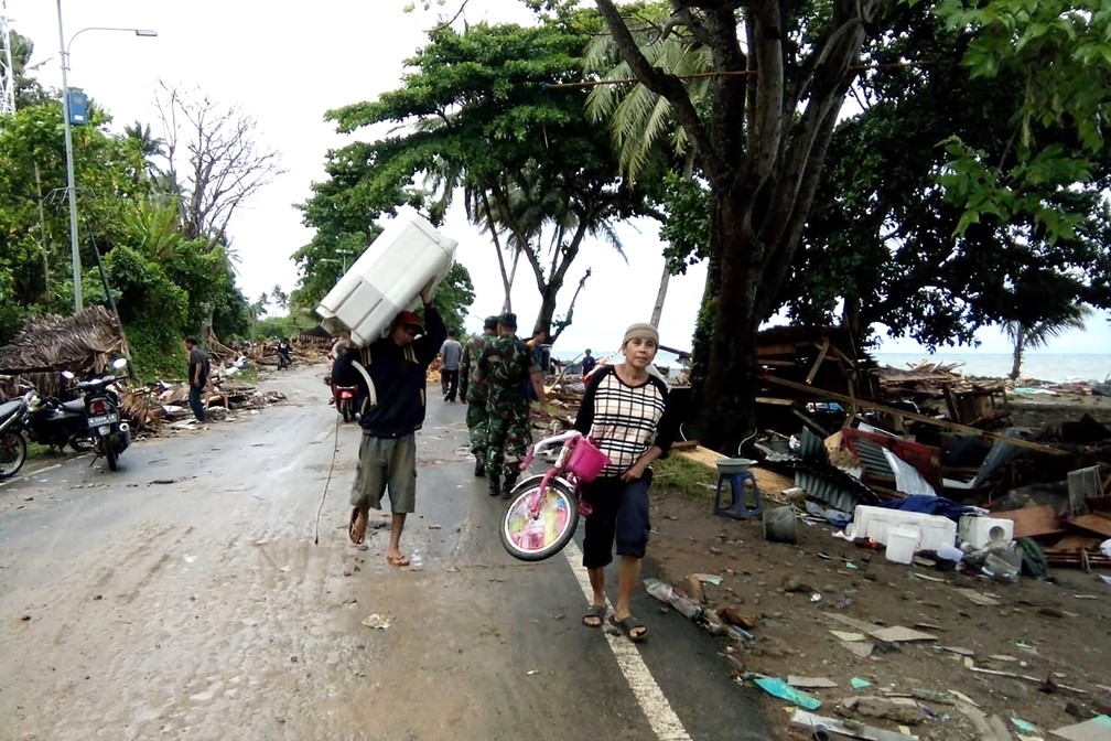 Moradores evacuam área destruída por Tsunami na praia de Carita — Foto: Semi / AFP