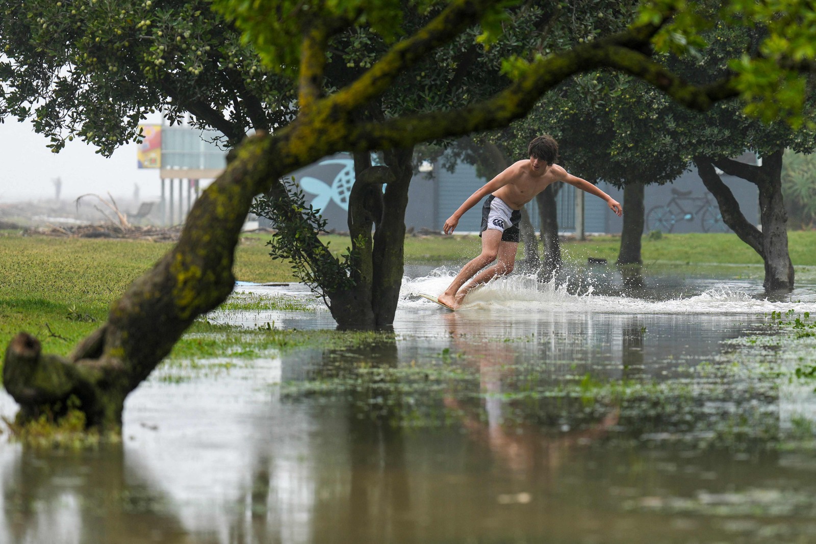 Homem surfa sobre as enchentes ao longo da Marine Parade na cidade de Napier, na Ilha Norte, da Nova Zelândia — Foto: AFP