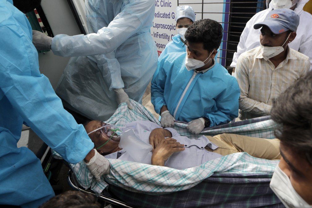 Profissionais de saúde carregam paciente com Covid-19 após incêndio em hospital em Virar, na Índia, nesta sexta (23) — Foto: Rajanish Kakade/AP