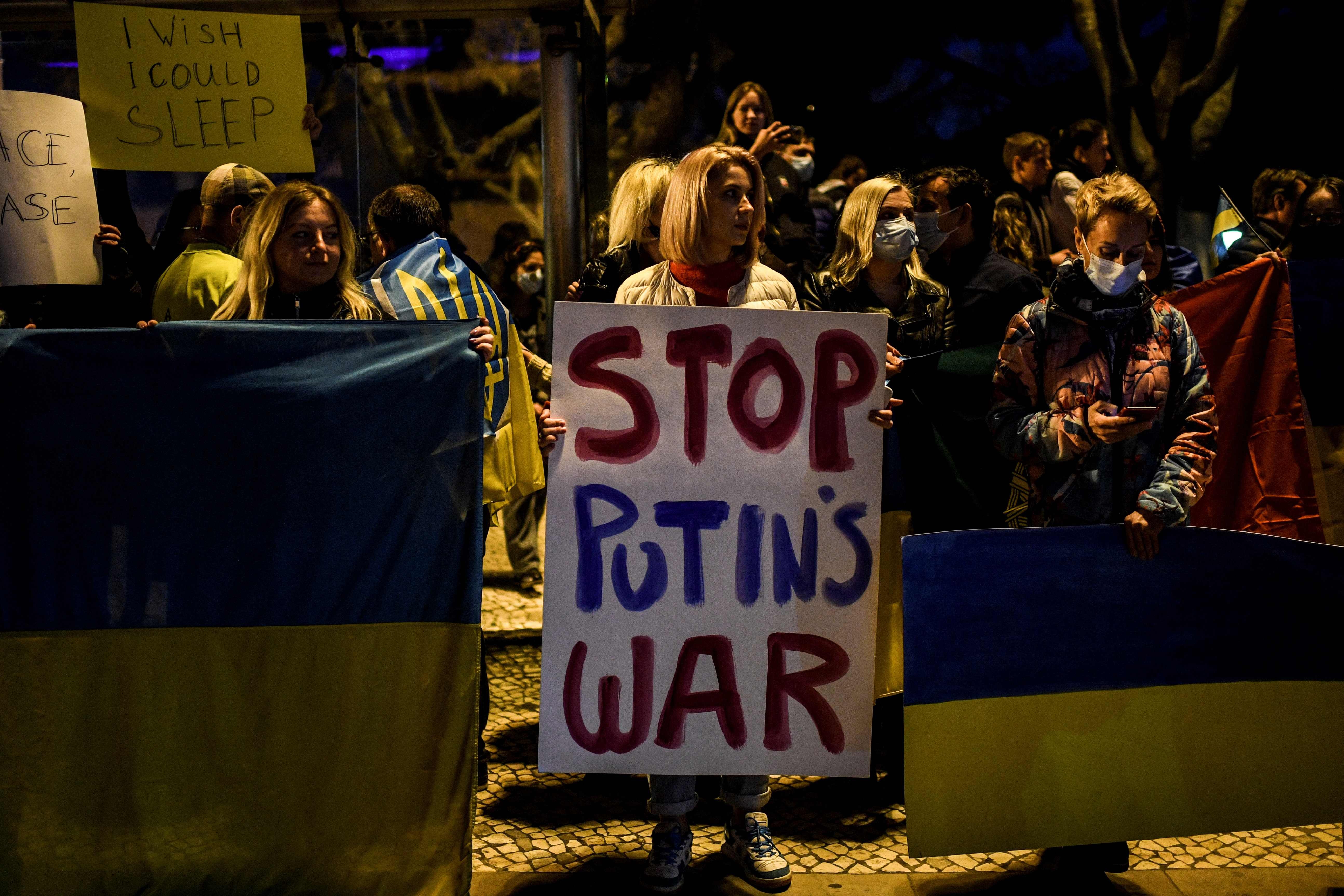 Em foto de fevereiro, manifestante exibe cartaz em Lisboa pedindo fim da guerra de Putin