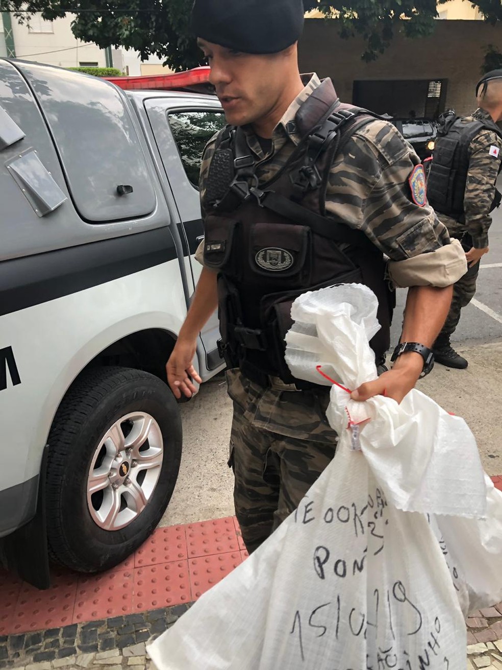 Policial com objetos apreendidos durante cumprimento de mandado em Belo Horizonte — Foto: Carlos Amaral/G1