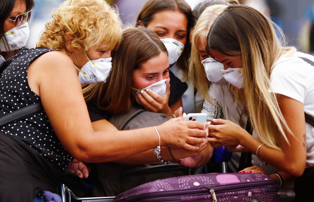 Viajantes com máscaras olham para celular no aeroporto internacional de Ezeiza, nos arredores de Buenos Aires, na Argentina, na sexta-feira (13)  — Foto: Marcos Brindicci/AP