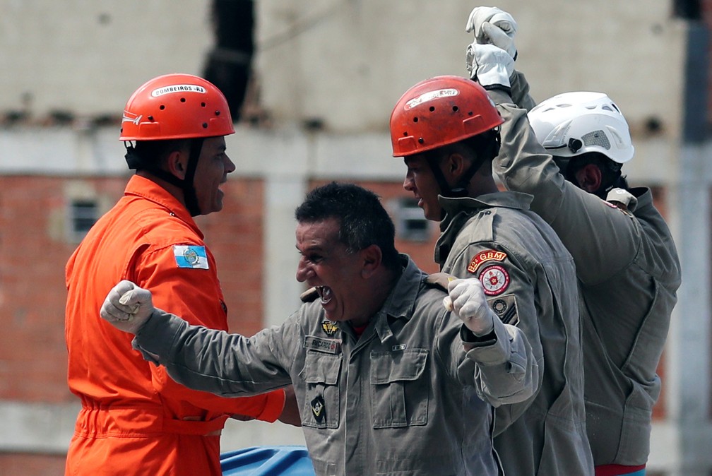 Bombeiros se emocionam após conseguir colocar ferido em helicóptero — Foto: Ricardo Moraes/Reuters