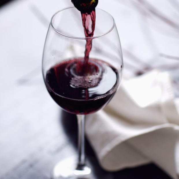 Elegant red wine pour in a fall setting with deep rich colors, twigs and napkin in the background. (Foto: Getty Images)