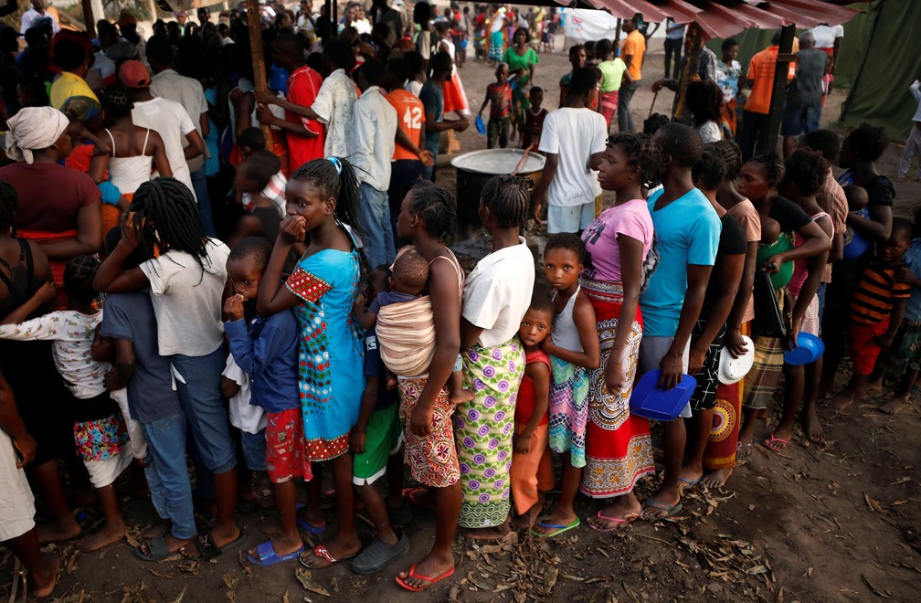 Pessoas esperam em fila por comida em um campo para desabrigados depois do ciclone Idai, na Beira, em Moçambique, nesta terça (26). — Foto: Reuters/Mike Hutchings
