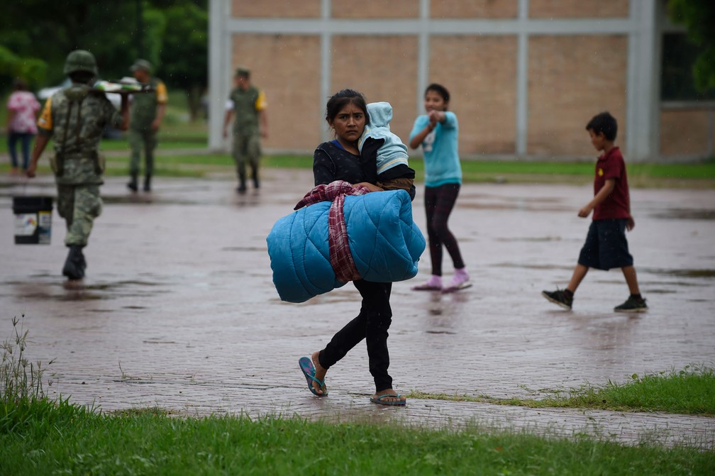 Mulher carrega bebê e seus pertences até abrigo em Escuinapa, em Sinaloa, no México, na terça-feira (23)  — Foto: Alfredo Estrella / AFP