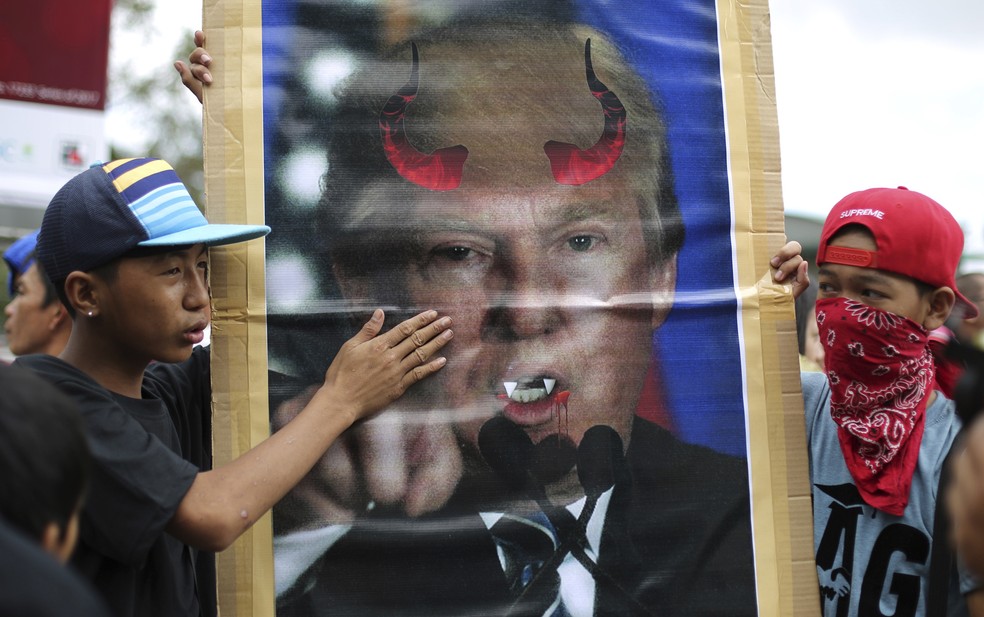 Muçulmanos seguram foto de Donald Trump com chifres e presas em protesto em Manila, nas Filipinas (Foto: Aaron Favila/AP)