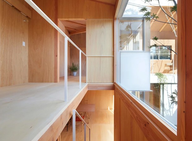 Para aumentar ainda mais a conexão entre os cômodos e aproveitar o espaço vertical, um mezanino fica em frente a uma grande janela (Foto:  Tomohiro Hata Architect & Associates/ Reprodução)