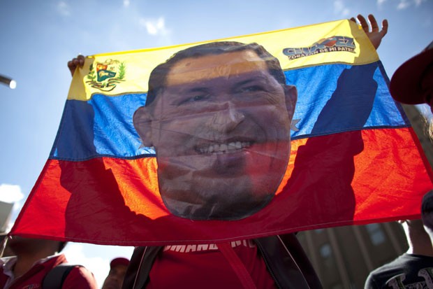 Apoiador de Chávez ergue uma bandeira com o rosto do presidente durante passeata em Caracas (Foto: Ariana Cubillos/AP)