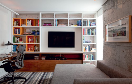 O arquiteto Maicon Antoniolli desenhou tanto o sofá, que serve de cama, quanto a estante com nichos, além da mesa de trabalho. O espaço une sala de TV, escritório e pode receber hóspedes eventualmente