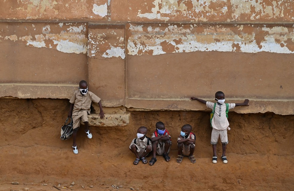 Crianças em idade escolar sentam-se do lado de fora da sala de aula em uma escola primária em Attecoube, popular distrito de Abidjan, na Costa do Marfim, na segunda-feira (25), no 1º dia após o reinício das aulas após o bloqueio por causa da pandemia de Covid-19 — Foto: Issouf Sanogo / AFP