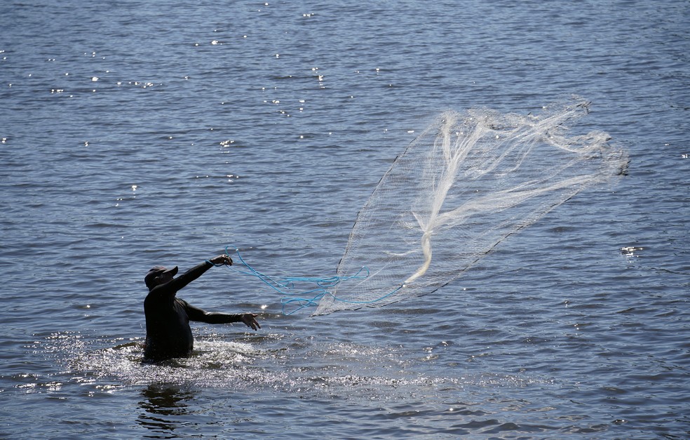Pescador joga tarrafa nas águas da Praia de Botafogo — Foto: Marcos Serra Lima/G1