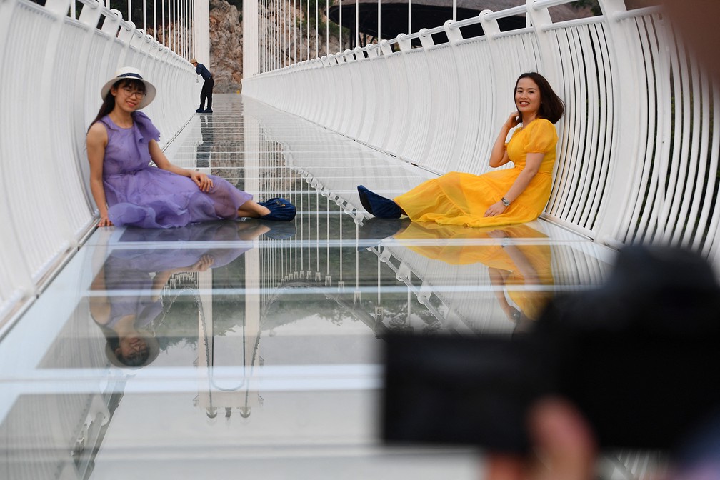 Duas garotas posam para fotos na maior ponte de vidro do mundo, no dia da inauguração, em em 29 de abril, no Vietnã. — Foto: Nhac Nguyen/AFP