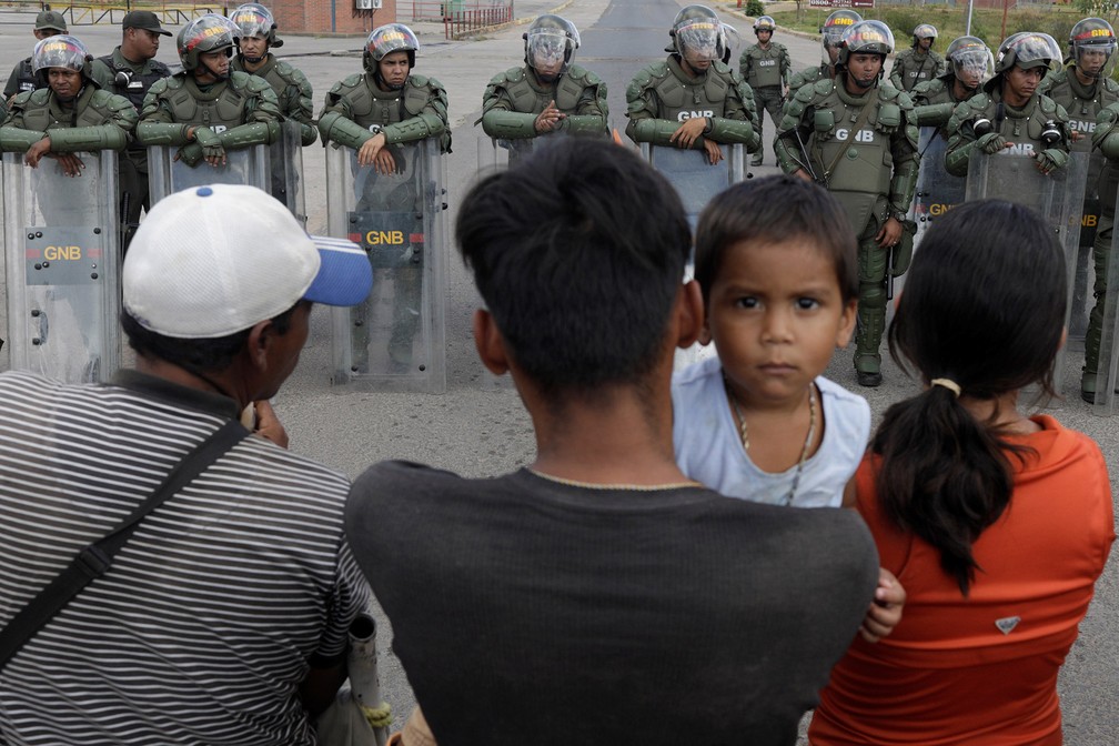 Na expectativa de cruzar a fronteira, pessoas aguardam diante de paredão de soldados venezuelanos em Pacaraima (RR) — Foto: Ricardo Moraes/Reuters