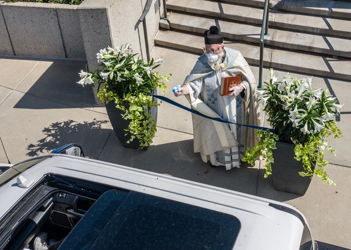 Padre Tim Pelc benze seus fiéis na porta da igreja com jatos de uma arminha de brinquedo (Foto: Reprodução/Facebook)