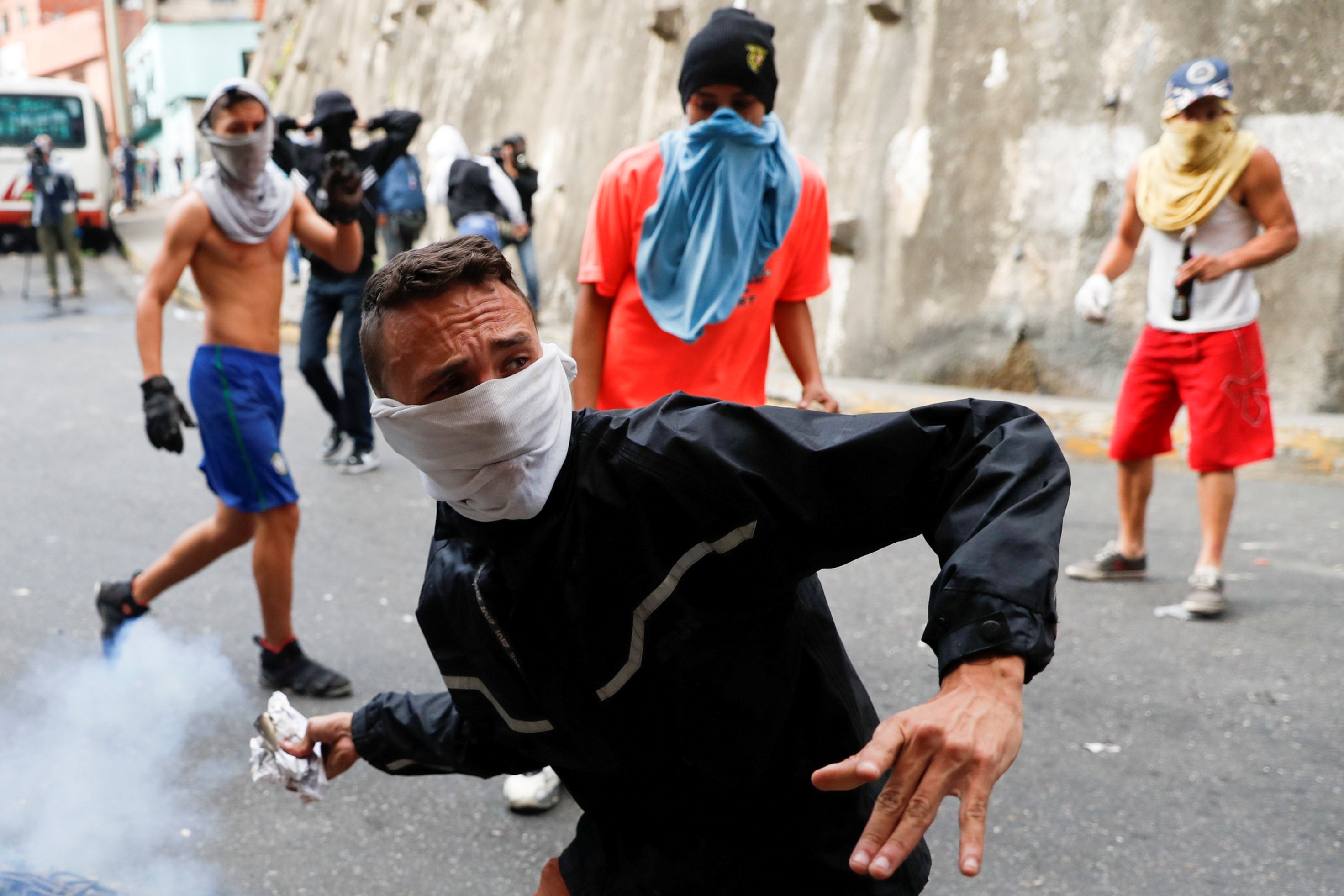 Manifestante joga de volta uma bomba de gás lacrimogêneo durante  protesto