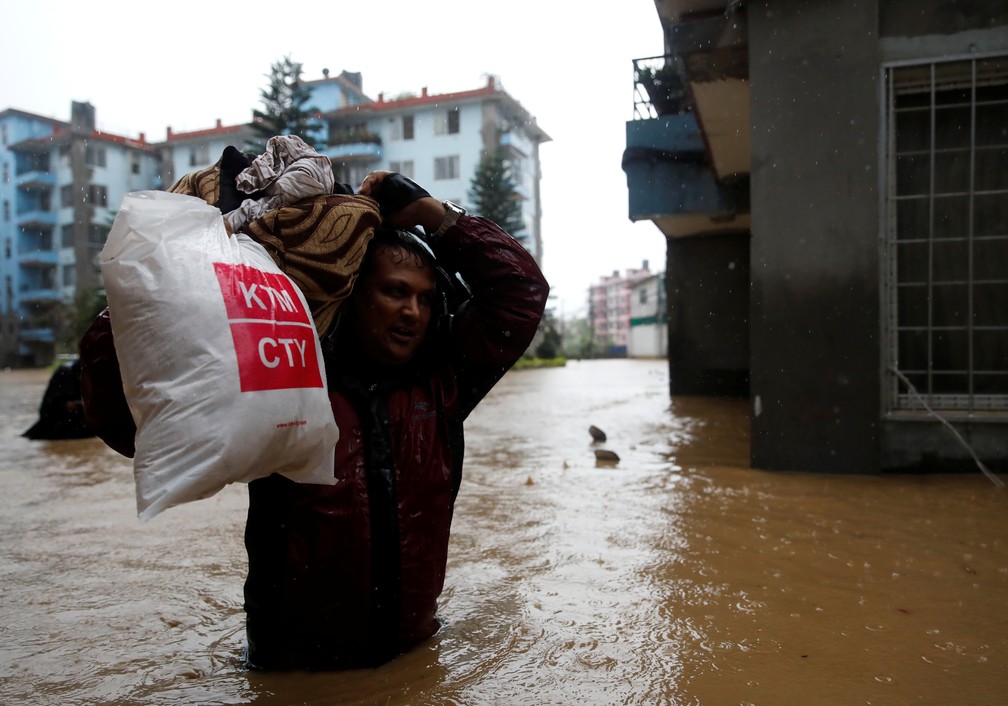 Homem carregando pertences anda em meio às inundações que atingiram Kathmandu, no Nepal, no dia 12 de julho. — Foto: Navesh Chitrakar/Reuters