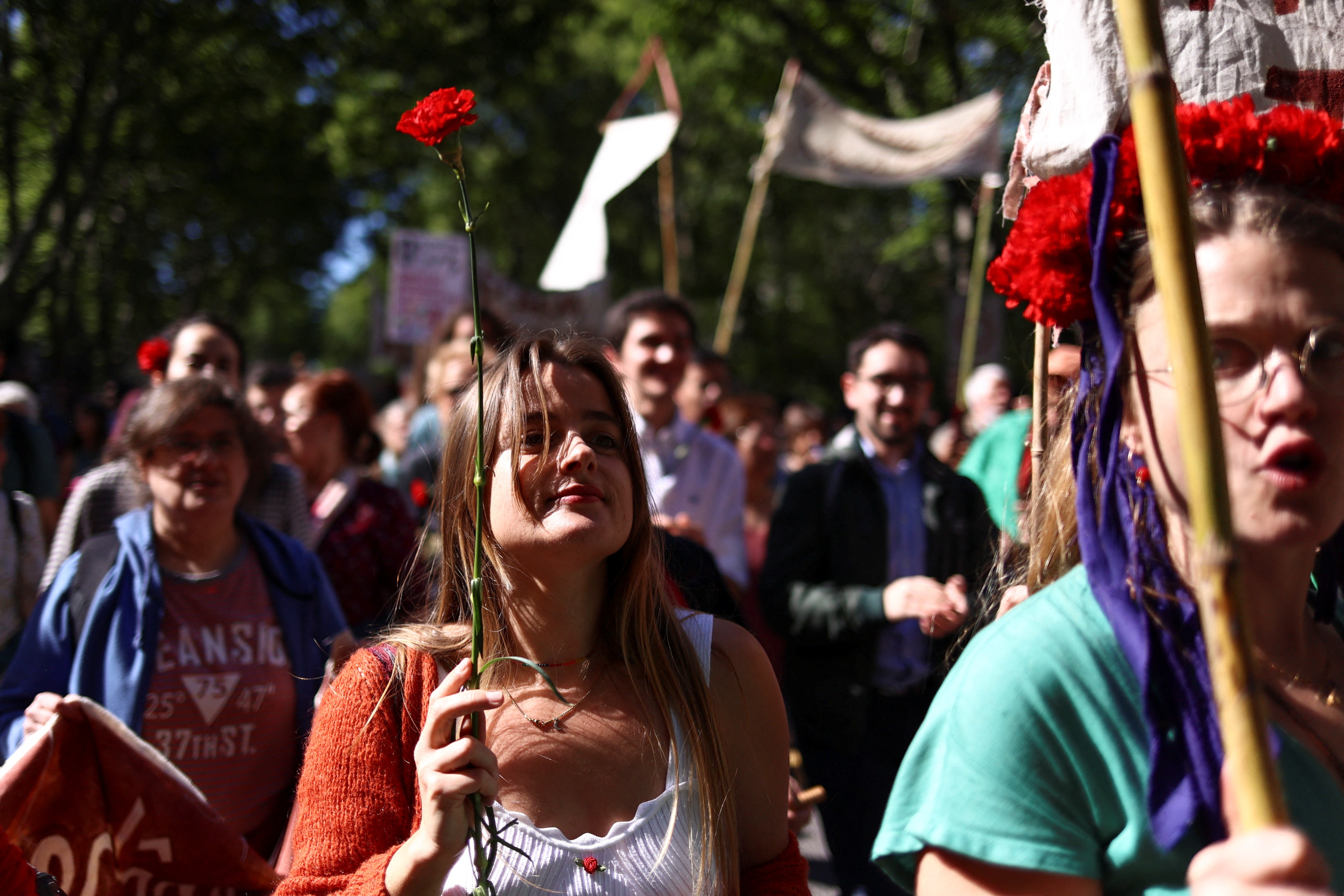 Mulher carrega um cravo em meio a outros participantes da celebração do 25 de Abril em Lisboa