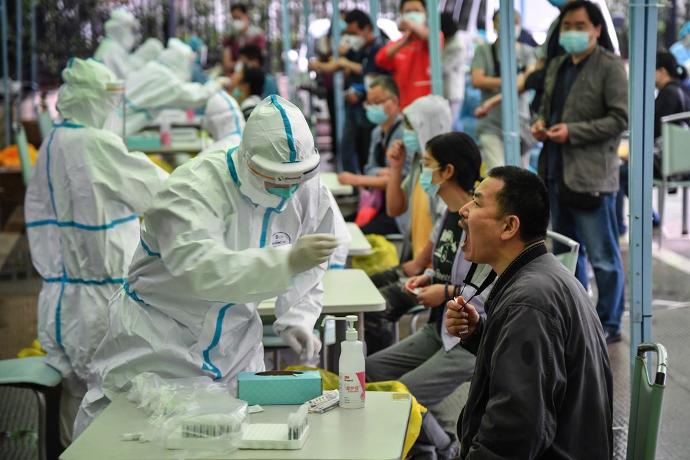 Profissional da saúde retira material para exame para detectar o novo coronavírus em Wuhan, na China. — Foto: AFP