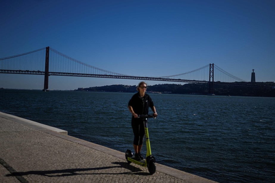 Mulher passeia de patinete elétrico na margem do Rio Tejo, em Lisboa