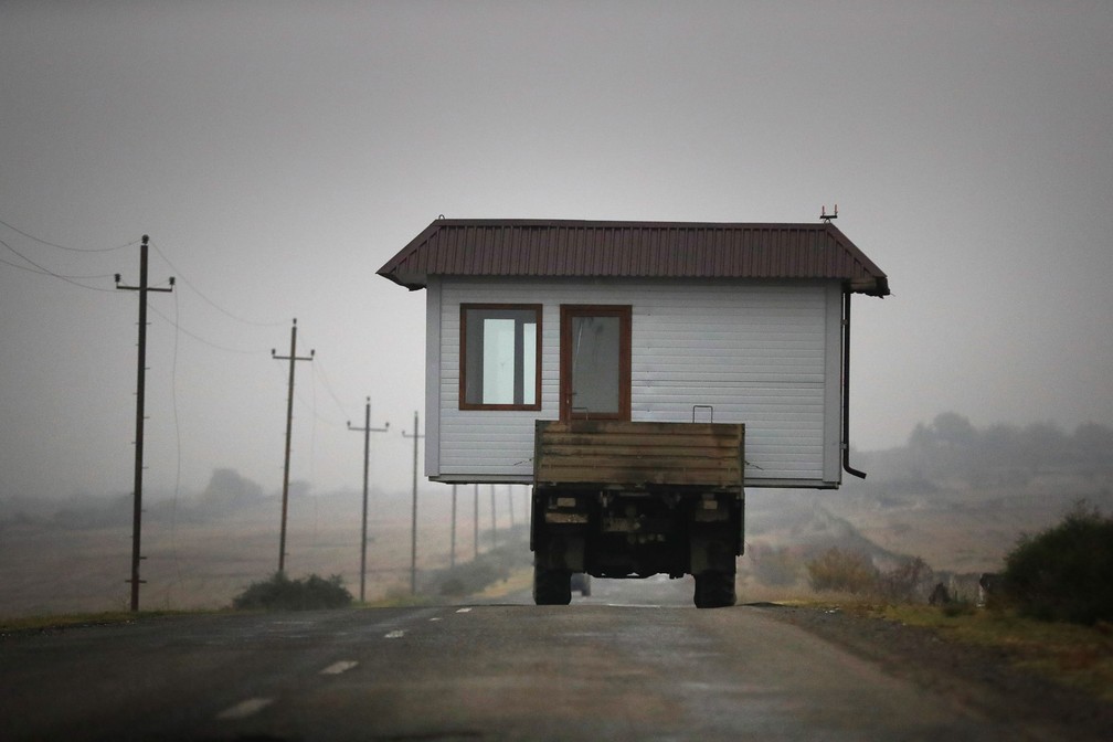 18 de novembro - Família leva sua casa na caçamba de um caminhão por rodovia após abandonarem uma vila na região separatista de Nagorno-Karabakh, atribulada por semanas de conflito entre Armênia e Azerbaijão que deixaram milhares de mortos — Foto: Sergei Grits/AP