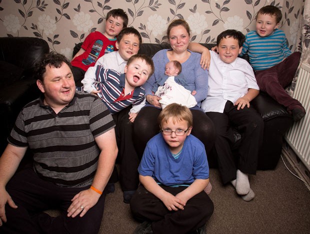 Louise Nutley segura a pequena Frayah ao lado do marido Dan (sentado) e dos filhos Benjamin, 12, Cameron, 11, Lewis, 9, Leighton, 8, Kieran, 7 e Ollie, 3 (Foto: The Grosby Group)