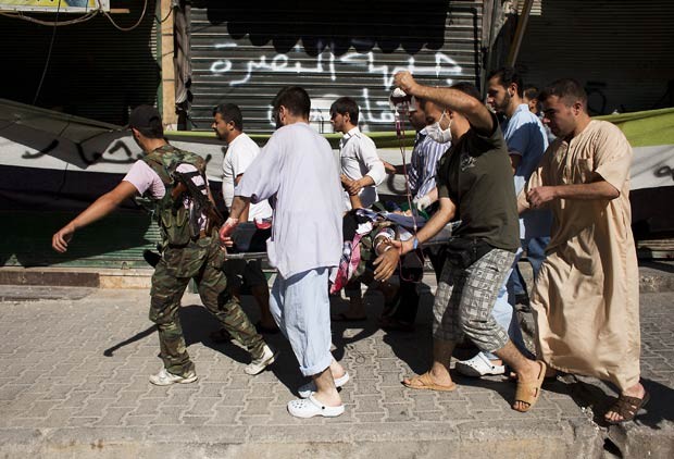 Rebeldes sírios carregam civil que teria sido atingido por franco-atirador nesta segunda-feira (20) na cidade síria de Aleppo (Foto: AFP)