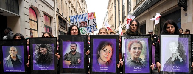 Manifestantes seguram retratos de ativistas curdos assassinados, durante uma marcha de tributo em Paris — Foto: Emmanuel Dunand/AFP
