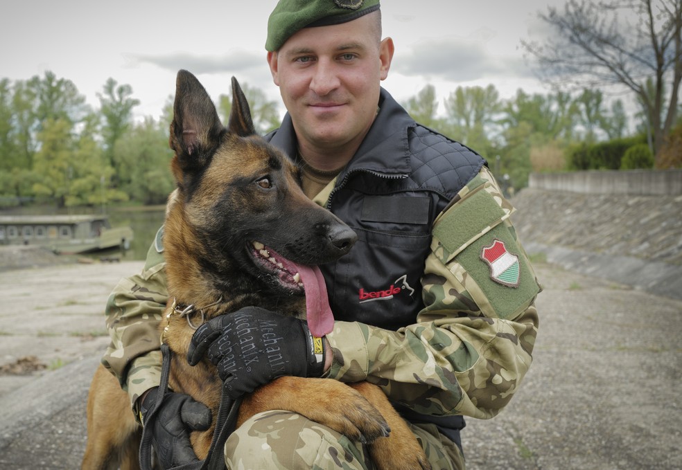 Sargento 1ª Classe Balazs Nemeth e seu cão farejador de bombas Logan  — Foto: AP/Bela Szandelszky