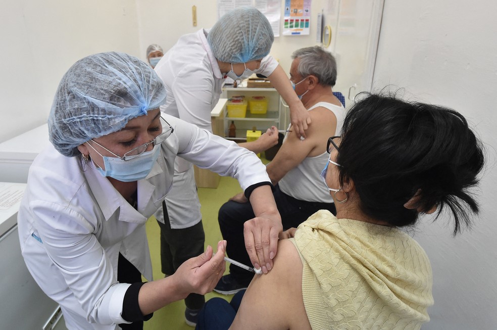 Profissionais de saúde vacinam pessoas com a Sputnik V em Bishkek, no Quirguistão, nesta terça-feira (27). — Foto: Vyacheslav Oseledko/AFP