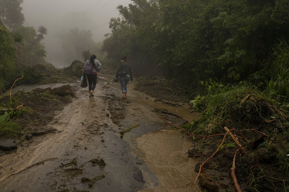 Mulheres caminham em estrada destruída no município de Comasagua, em En Salvador, após passagem da tempestade Julia pela América Central, em 10 de outubro de 2022. — Foto: Moisés Castillo/ AP