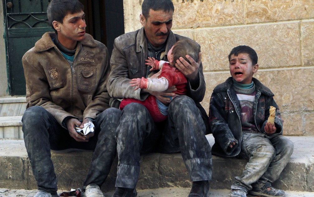 Homem segura bebê salvo de escombros do que ativistas dizem ter sido um ataque de forças leais ao presidente Bashar al-Assad, em Aleppo, na Síria, em 14 de fevereiro de 2014 — Foto: Reuters/Hosam Katan